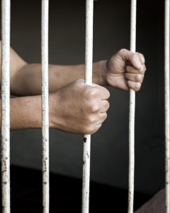 Hands of man prisoner gripping rusty prison bars