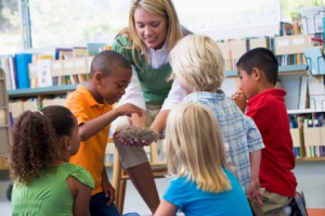 Kindergarten teacher and children looking at bird's nest in libr