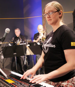 Becky Guy (keyboard), Randy  Dimond (left), Eric Vincent (Trombone) play for the Promega Employee Recognition Meeting as part of Lead Generation.