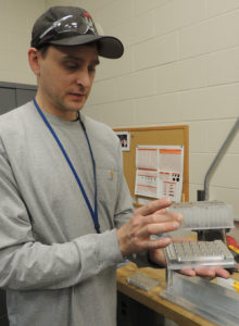 Travis shows the part he redesigned for the Promega Maxwell® instrument.