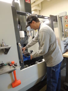 Travis prepares the milling machine to take another part.
