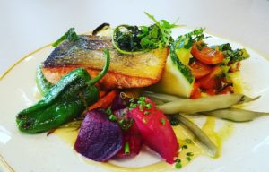 Salmon with summer vegetables and edible flowers. An employee posts a photo of their Promega lunch on social media. #LifeatPromega
