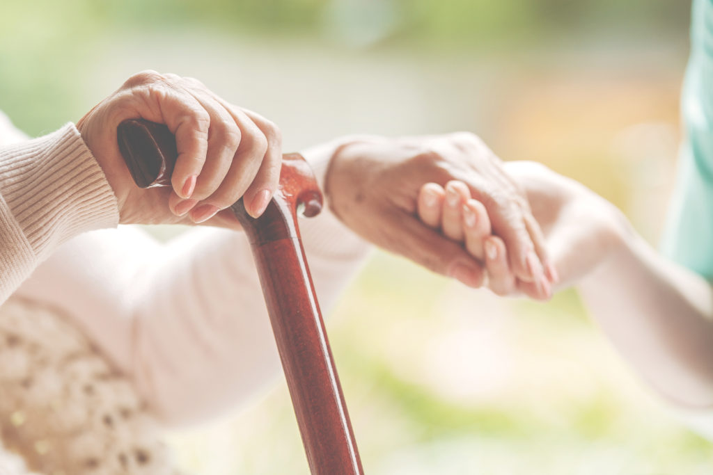 Picture shows a younger person helping an elderly person. Supporting caregivers is essential.
