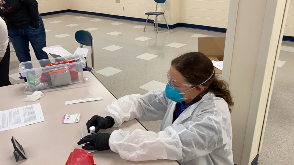 Shelby O'Connor works with an antigen test for COVID-19