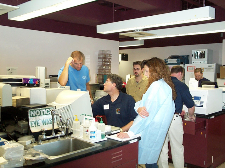 Allan Tereba (center, blue polo) works with technicians at the New York City Office of the Chief Medical Examiner (OCME) in September 2001 to discuss automating forensic DNA purificaiton.