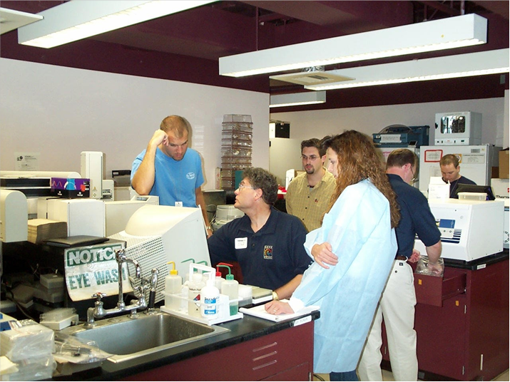 Allan Tereba (center, blue polo) works with technicians at the New York City Office of the Chief Medical Examiner (OCME) in September 2001 to discuss automating forensic DNA purificaiton.