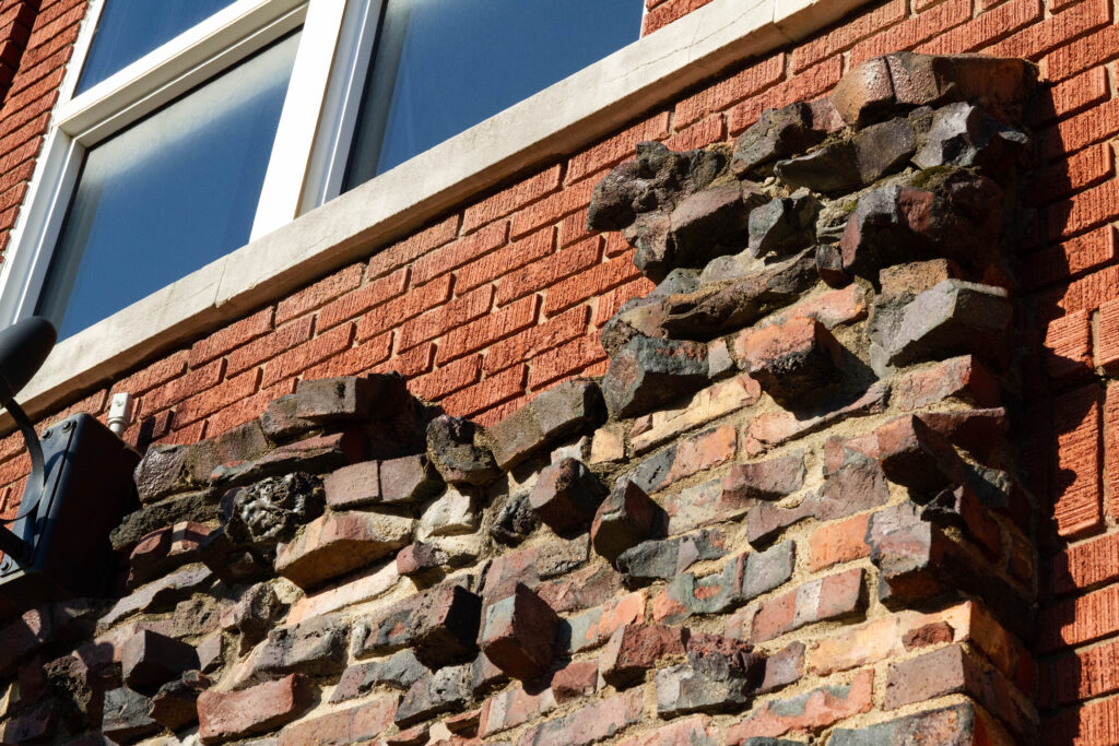 Old, blackened bricks are incorporated into a building's modern brick facade. 