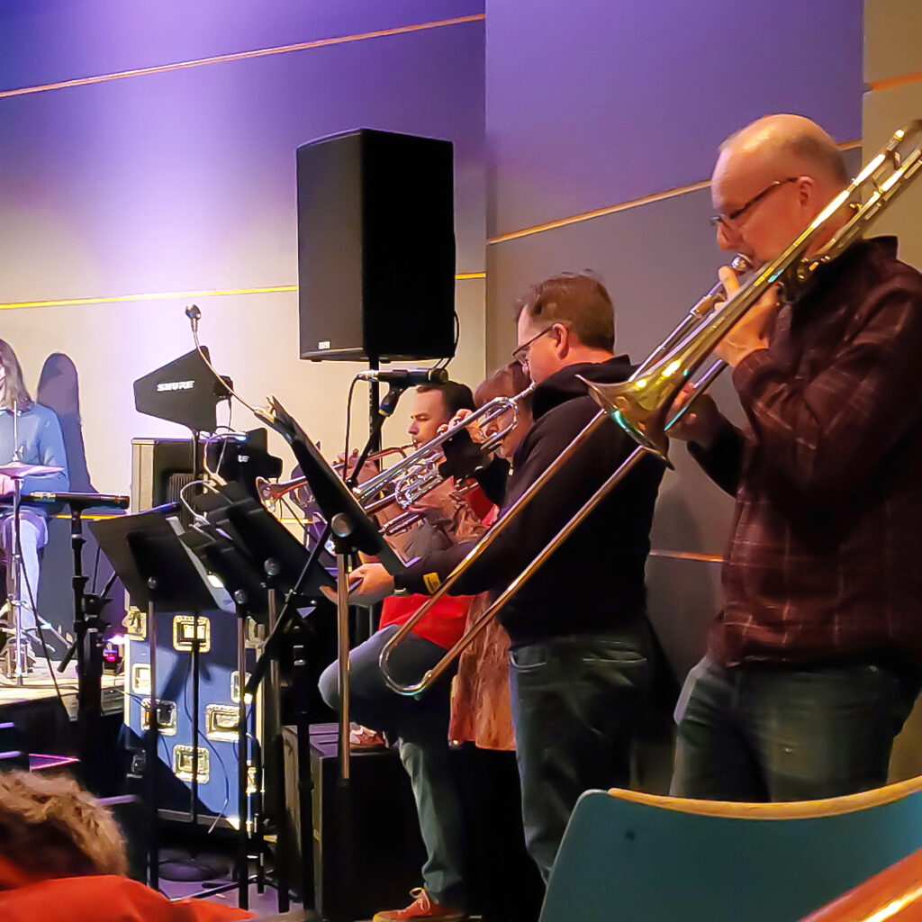 A group of employees play brass instruments during a Major Groove performance