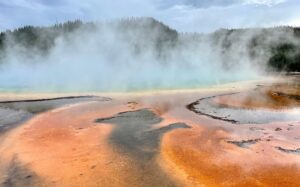picture of grand prismatic hot spring; steam rising up from orange and yellow hot springs pools