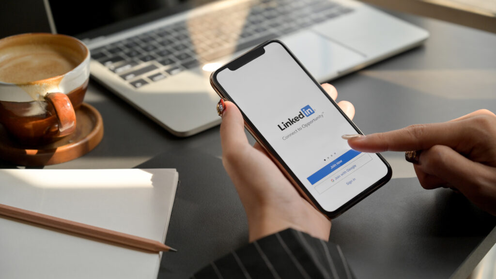 female holding iPhone with LinkedIn screen. LinkedIn helps build portfolio and look for a new job