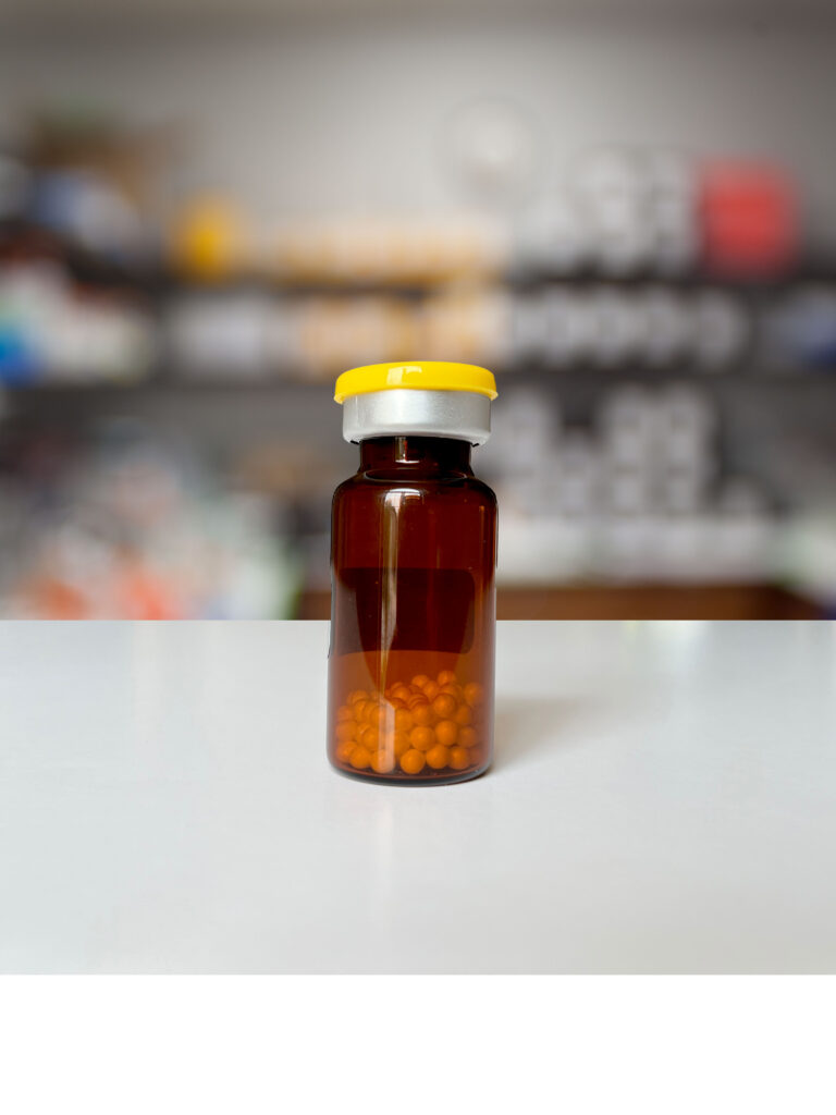 Amber glass bottle filled with lyophilized beads sitting on a lab bench.